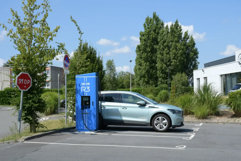 Voiture électrique en cours de recharge sur une borne rapide installée sur un parking extérieur, infrastructure de mobilité durable favorisant la transition énergétique et l’utilisation de véhicules électriques.