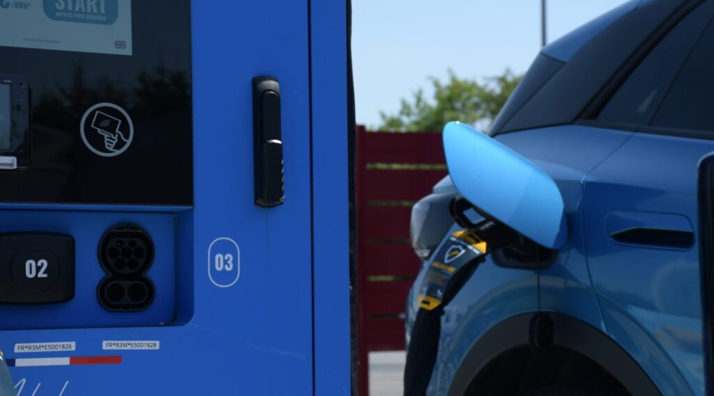 Photo qui montre une voiture électrique avec une borne de recharge de voiture électrique
